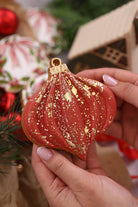 Red and gold bauble cookie held in hand