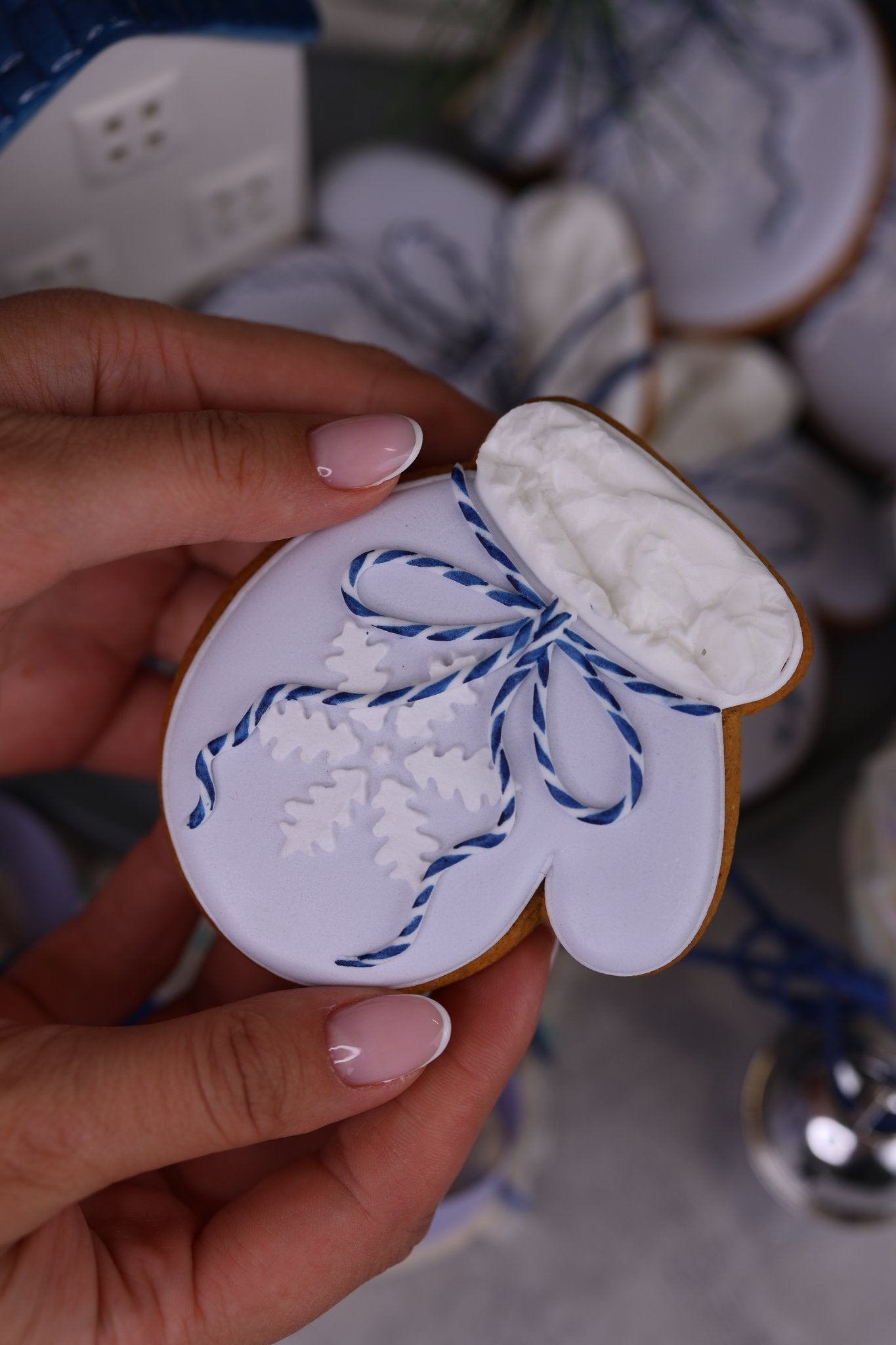 Mitten cookie with stencilled snowflakes and a blue bow